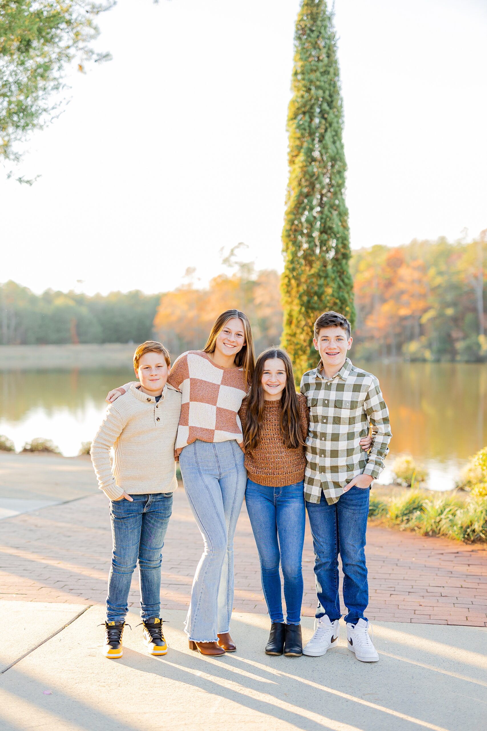 four teenagers hug by lake during fall family photos 