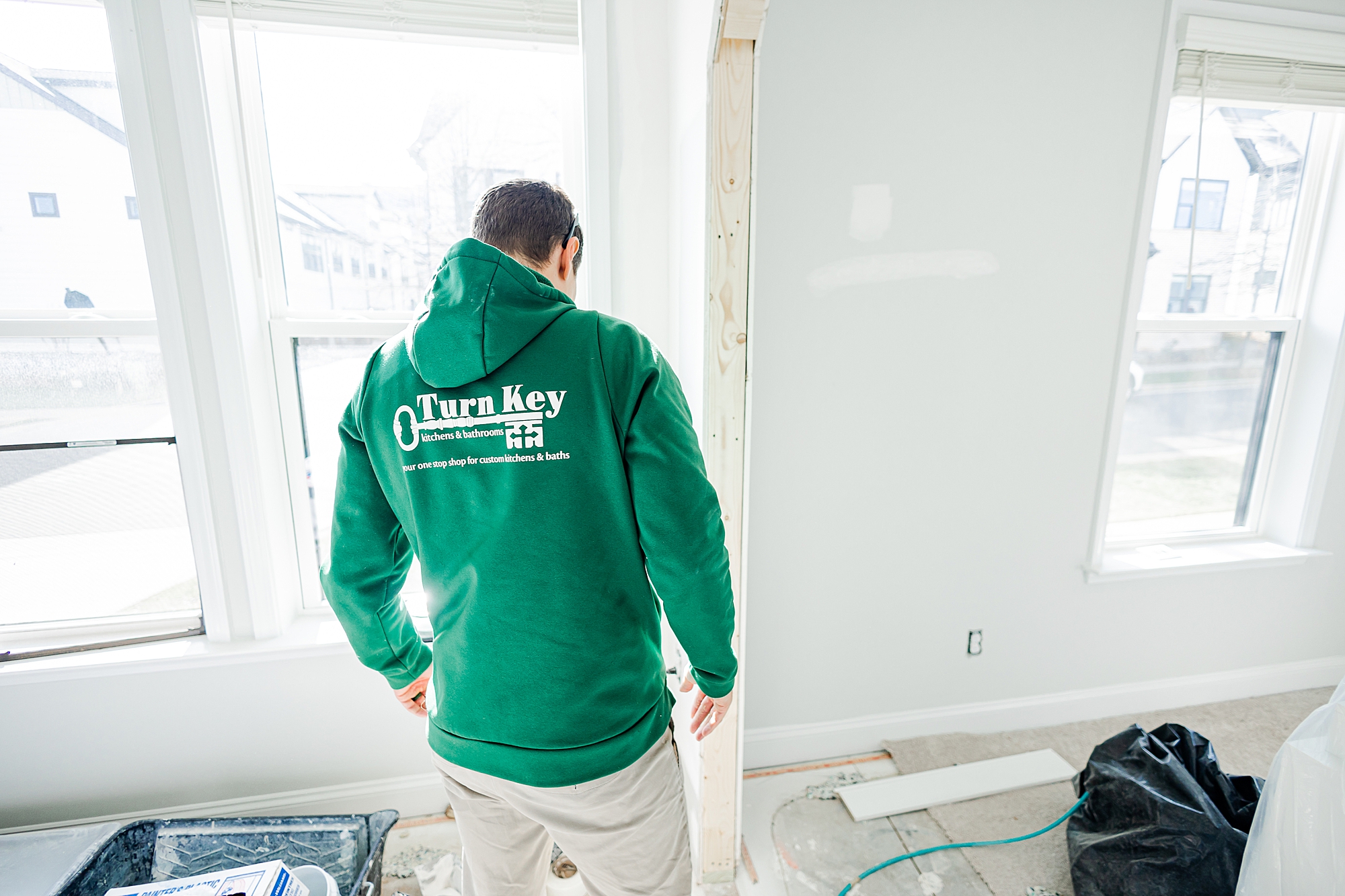 contractor in green sweatshirt looks at floor during renovations with Turn Key Solutions