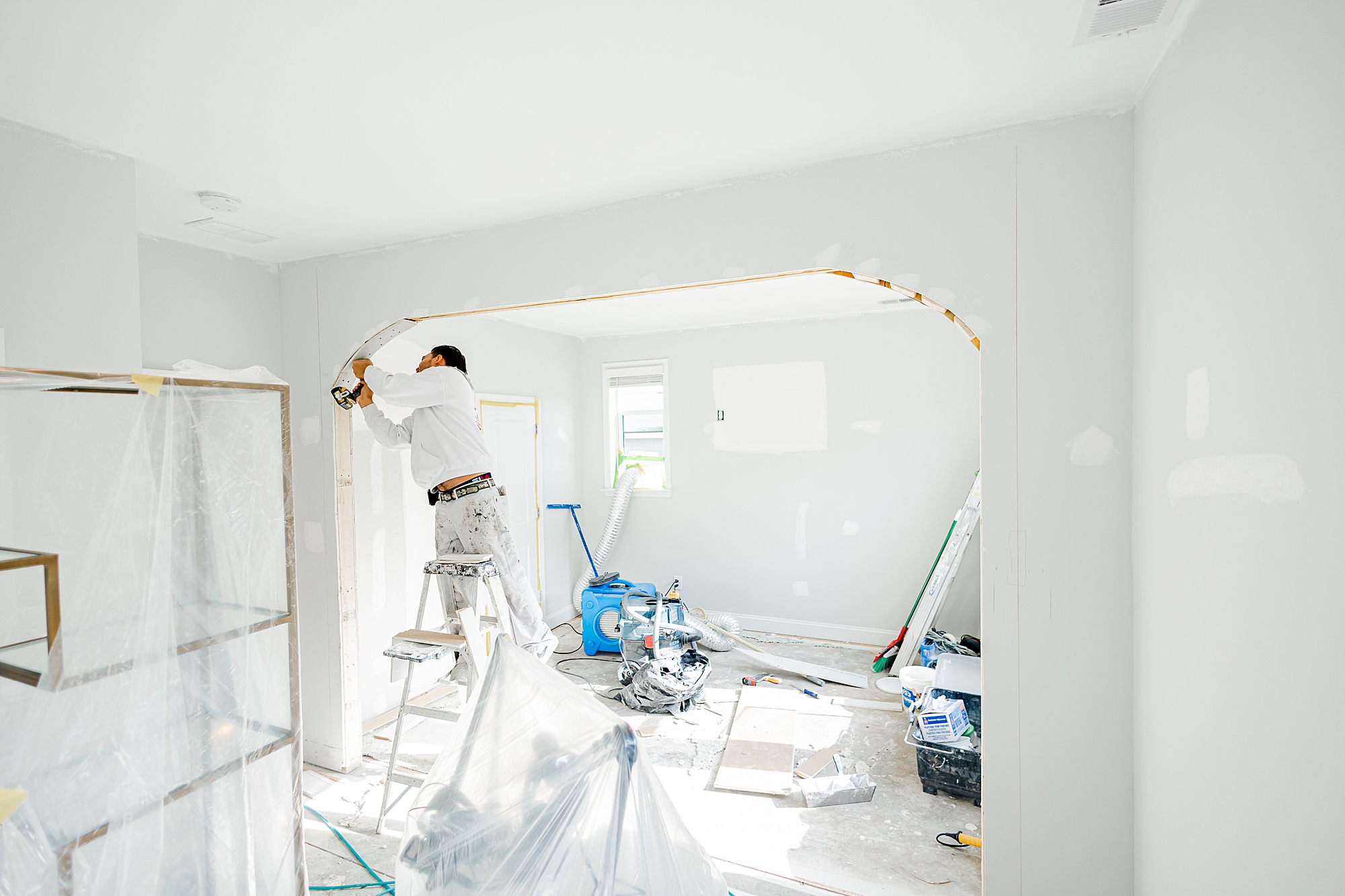 worker paints beam between rooms 