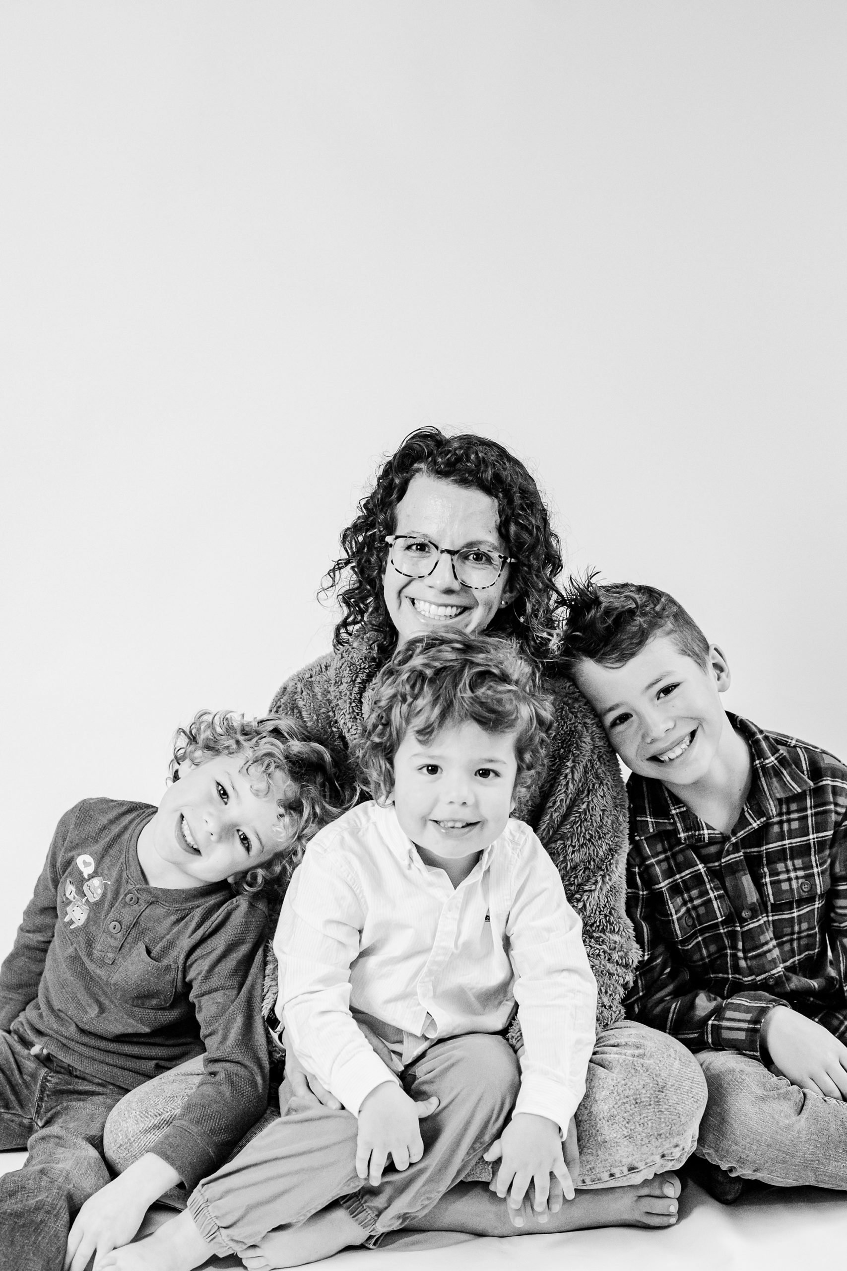 mom sits with three boys during personality portraits in Charlotte Studio