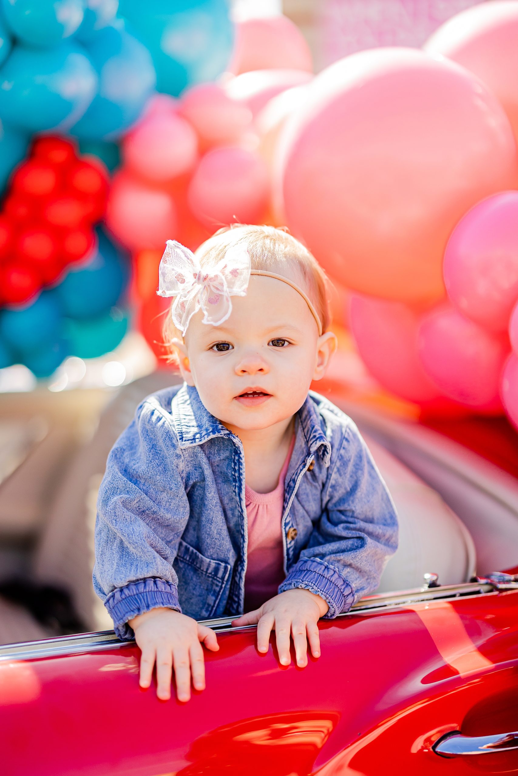 baby leans on side of red Thunderbird during Valentine's Day photos 