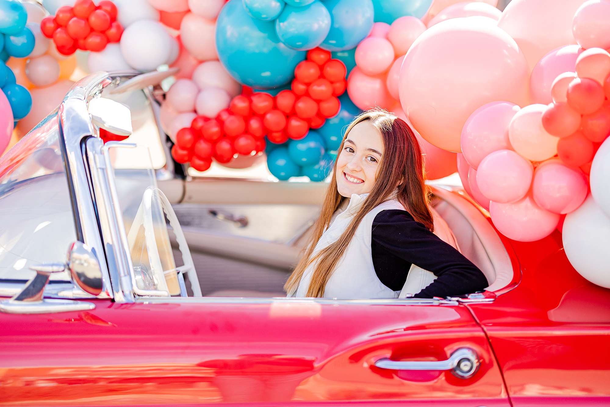 woman sits in red Thunderbird during Valentine’s Day photos