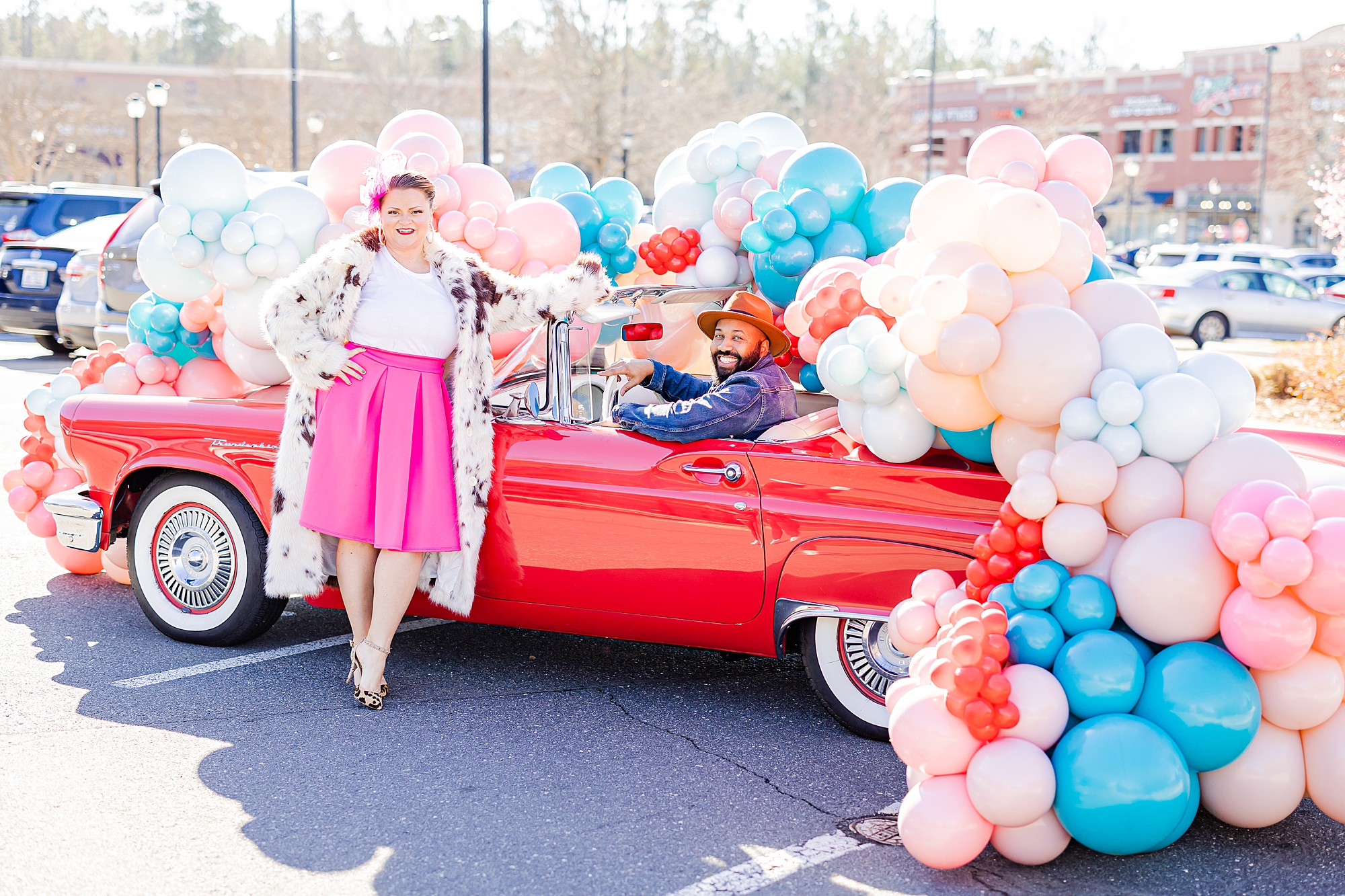 woman leans on red Thunderbird in pink skirt at Sips and Dips