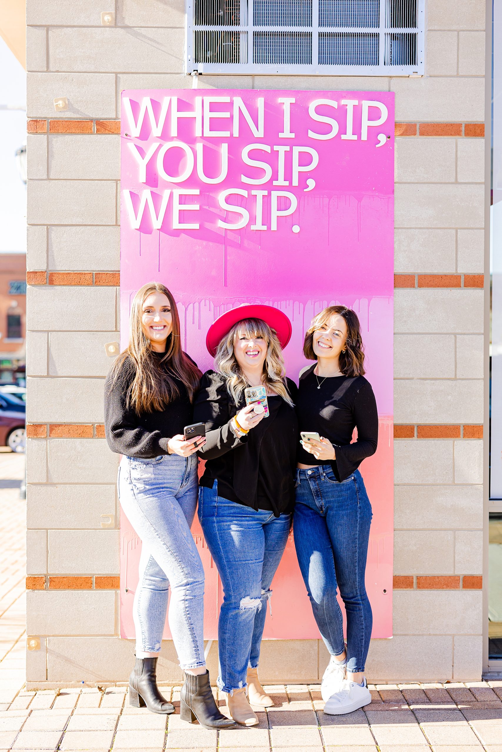 three women pose by pink sign at Sips and Dips in Charlotte NC