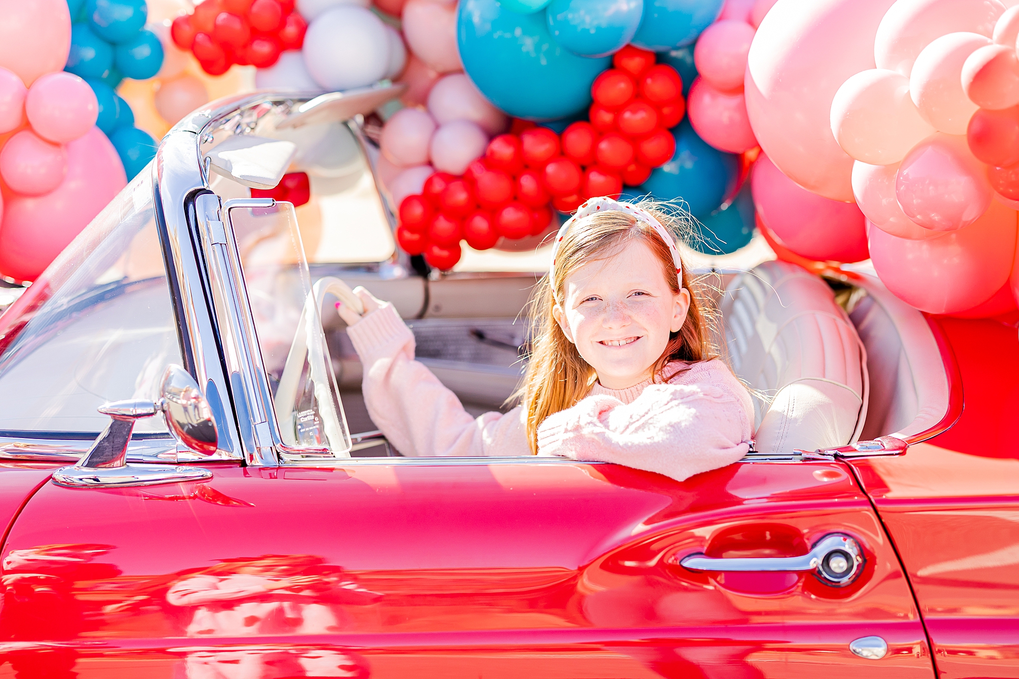 girl sits in front of red Thunderbird during Valentine’s Day Thunderbird Photos