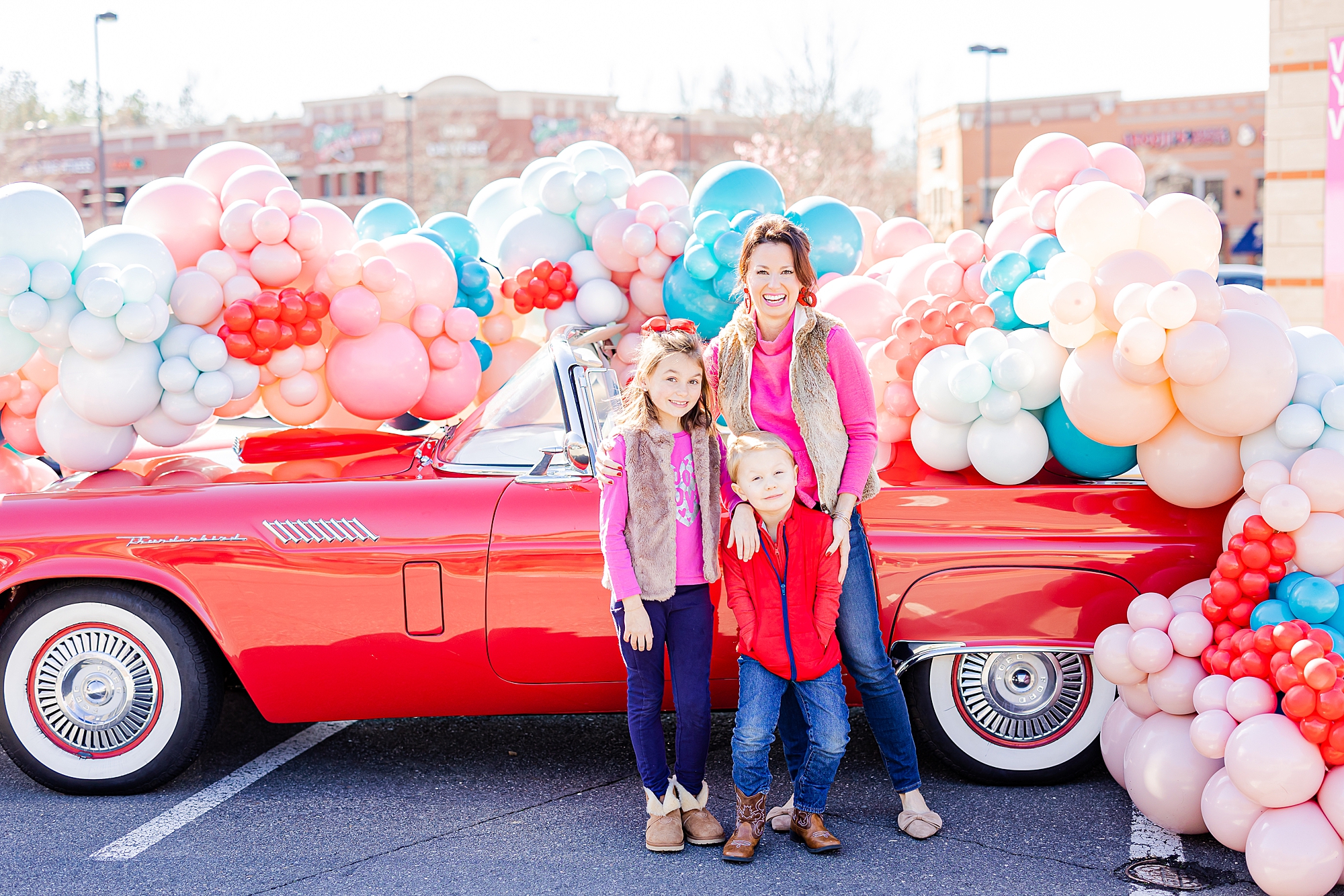 siblings pose together by red Thunderbird during Valentine’s Day Thunderbird Photos