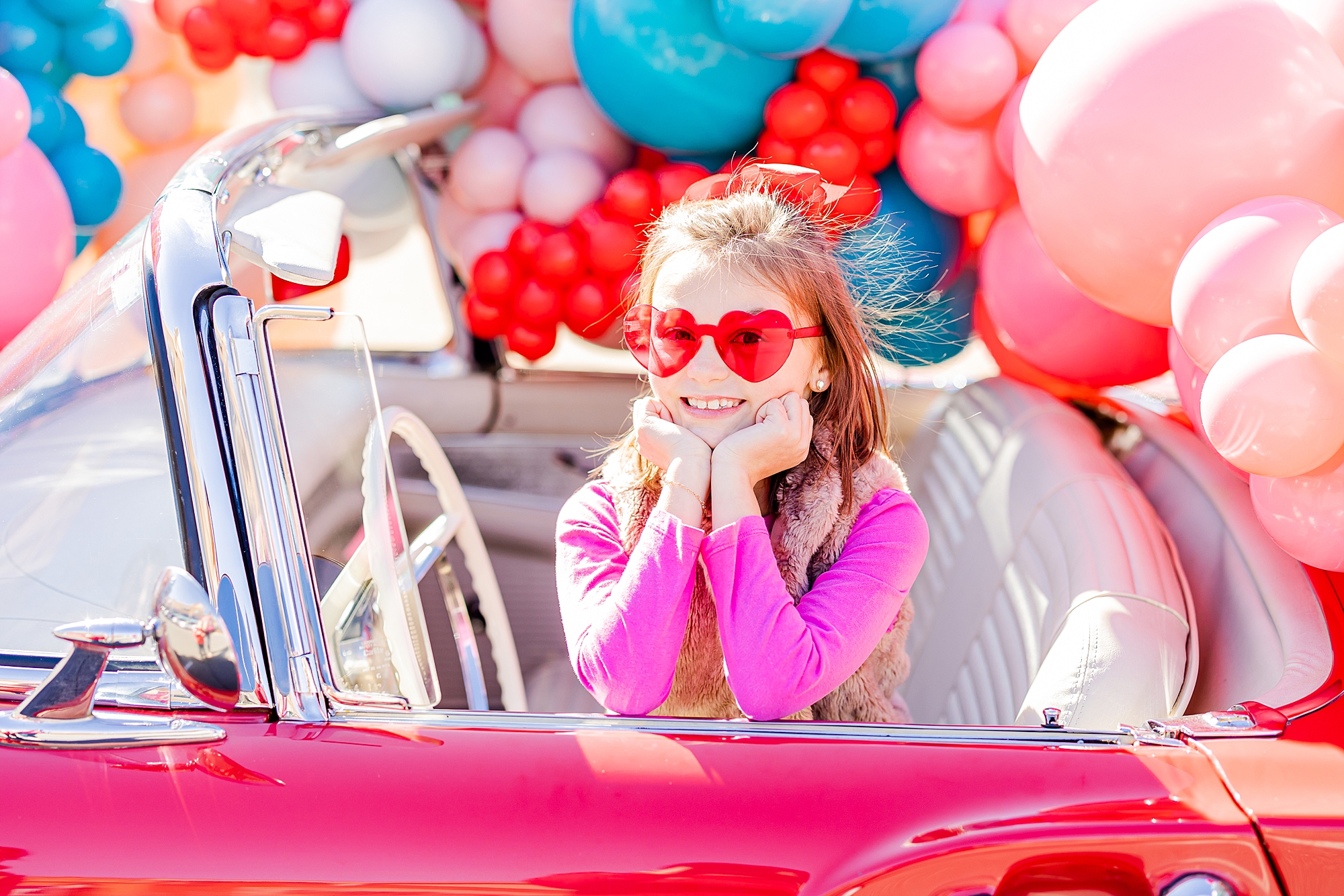 girl in heart glasses leans on side of car during Valentine’s Day Thunderbird Photos